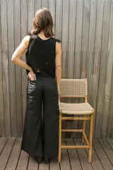 Chaleco negro de gamuza con cuello redondo y detalle de plumas en los hombros. Presenta un diseño sin mangas y corte recto, ideal para usar como top o prenda de superposición.