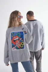 Buzo gris melange de corte holgado con cuello redondo y mangas largas. Estampado frontal con diseño de estampilla con labios, guitarra y la letra B.
