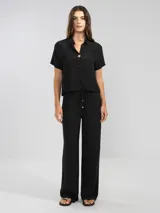 Pantalón palazzo negro de crepe con cintura elastizada, bolsillos laterales y terminaciones en cobre.