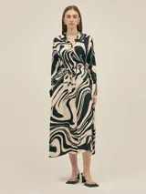 Vestido largo estilo camisero confeccionado en seda viscosa con estampado abstracto en blanco y negro. Cuenta con botones nacarados, bolsillos laterales, lazo para ajustar en la cintura y aberturas laterales.