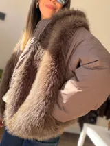 Campera puffer oversize color marrón, con paneles frontales y traseros de pelo sintético suave. Presenta mangas acolchadas, cierre frontal y bolsillo con cierre en la manga.