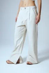 Pantalón sastrero de gabardina color beige, con pinzas delanteras, presillas anchas en la cintura y tajo interno en la botamanga.
