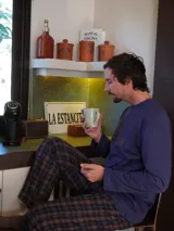 Pijama de algodón premium compuesto por una camiseta de manga larga color azul con logo bordado en el pecho y un pantalón largo de corte recto con estampado de cuadros en tonos marrones y azul.