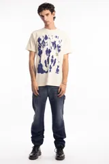 Remera de algodón color beige con estampado abstracto en azul marino y texto pequeño en el frente.