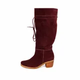 Bota de caña alta color suela, confeccionada en cuero napa, con diseño de caña caída y ajuste mediante cordones en la parte superior. Presenta un taco cuadrado foliado de 4,5 cm y suela de goma antideslizante.