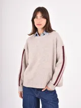 Buzo de tejido de punto en color beige, con cuello redondo, mangas largas y detalle de franjas verticales en color bordó a lo largo de los brazos.