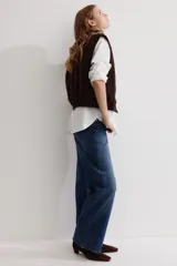 Chaleco de lona de algodón con terminación encerada en color marrón, levemente acolchado. Presenta un cuello de pana a tono, cierre frontal de cremallera, bolsillos laterales insertados y cintura elástica con frunces.