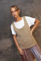 Top tejido a crochet en color dorado con destellos brillantes, de escote redondo y sin mangas. Presenta un diseño de flecos largos en la parte inferior en tonos rojo y dorado.