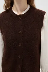 Chaleco de punto texturizado en color marrón chocolate, con cuello redondo y cierre frontal de botones a tono.