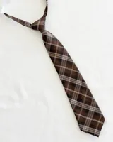 Corbata infantil marrón con estampado de cuadrillé en tonos marrón, beige y blanco. Tiene un elástico ajustable al cuello.