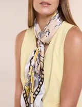 Pashmina satinada con estampado floral en tonos amarillo, blanco y gris, de forma cuadrada, e incluye un broche metálico decorativo.
