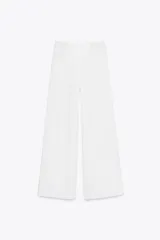 Pantalón palazzo blanco de tiro medio, pierna ancha y cintura ajustable con cordones. Presenta bolsillos laterales ocultos en costura.