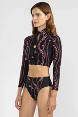 Crop top de bikini negro con estampado de cadenas rosadas, cierre frontal con tirador de flor, cuello alto y mangas largas.