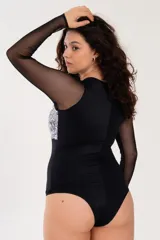 Body negro con mangas largas de microtul, escote redondo y parte superior de puntilla con diseño floral en blanco y negro.