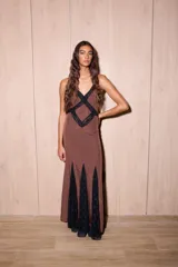 Vestido largo de seda color marrón con estampado de lunares blancos y detalles de encaje negro. Presenta un diseño entallado en el torso, escote en V profundo y espalda descubierta con tiras cruzadas.