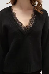 Sweater negro de punto con escote en V profundo y detalle de encaje en el borde del cuello. Presenta mangas largas con puños acanalados y un corte holgado.