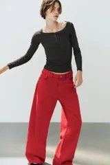 Jeans estilo baggy oversize de tiro medio en color rojo, con cinco bolsillos, trabillas para cinto y costuras decorativas marcadas en las piernas.