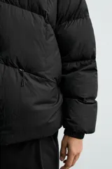 Cazadora acolchada de corte relajado confeccionada en tejido técnico color verde militar. Presenta cuello subido, cierre frontal con cremallera, mangas largas con puños elásticos y bolsillos frontales con cremallera oculta.