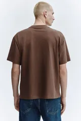 Remera de algodón color marrón, con cuello redondo y diseño de corte relajado con hombros caídos.