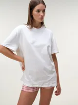 Remera oversize de manga corta al codo, color blanco, con cuello redondo y diseño amplio y relajado.