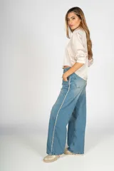 Pantalón de jean celeste de corte wide leg con detalle de flecos blancos en los laterales.