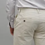 Pantalón de gabardina color azul marino, de corte ajustado y tiro medio, con cierre y botón frontal.