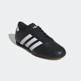 Championes Adidas de cuero negro con las tres tiras blancas y suela marrón.