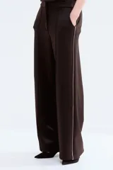 Pantalón sastrero de tejido efecto neopreno color marrón oscuro, de corte recto con raya central pespuntada y franja lateral en color rosado contrastante. Cuenta con bolsillos al bies y cierre frontal con botón oculto y corchete.