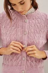 Cardigan de punto calado en color rosado, con cuello redondo y cierre frontal de botones decorativos con pedrería brillante.
