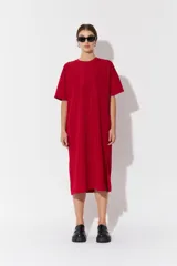 Vestido largo de manga corta y corte oversize, confeccionado en tejido con textura. Presenta cuello redondo y un parche decorativo en la parte posterior.