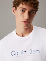 Remera blanca de algodón con cuello redondo y logo Calvin Klein estampado en azul en el pecho.