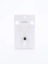 Cadena fina de color dorado con un dije colgante compuesto por una pieza superior negra y una piedra blanca en forma de colmillo.