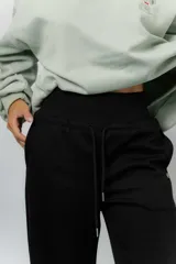 Pantalón blanco de silueta amplia y caída fluida, con cintura alta elastizada y lazo regulable con terminaciones metálicas.