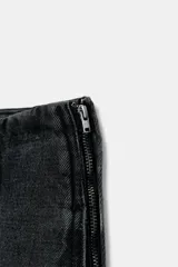 Jeans de tiro alto con diseño de pierna tipo balloon, confeccionados en denim de color gris oscuro con efecto lavado. Presentan costuras verticales marcadas a contraste, bolsillos laterales ocultos y cierre lateral con cremallera.
