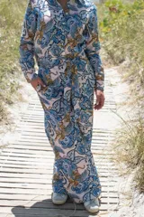 Pantalón de corte recto con estampado de flores, hojas y tigres alados en tonos celeste, azul y ocre.