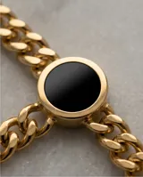 Collar de cadena tipo eslabón grueso con baño de oro, que presenta tres dijes circulares con piedra ónix negra y detalles de números romanos en los bordes.