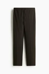 Jogger de vestir color marrón oscuro, de corte slim fit con pliegues frontales y traseros, cintura elástica con cordón de ajuste y bolsillos al bies.