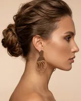 Caravanas colgantes de acero en tono rose gold, compuestas por un disco superior liso y una estructura inferior formada por múltiples aros entrelazados de textura trenzada.
