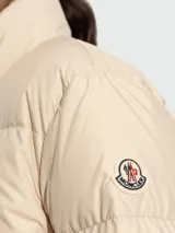 Campera puffer Moncler Mauzun color beige, con cuello alto, cierre frontal de doble carro y diseño acolchado horizontal.