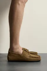 Zapato estilo náutico fabricado en piel con acabado serraje, con detalle de bordón en el empeine, horma redonda y suela ultrafina a contraste.