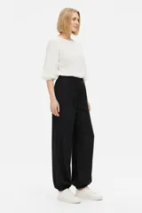 Pantalón de viscosa color negro, holgado de tiro alto, con bolsillos laterales, detalles de frunces en la cintura y botamangas elastizadas.