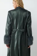 Trench largo de efecto cuero en color verde oscuro, con acabado brillante, cuello solapa, cinturón ajustable a la cintura y puños con detalle de pelo sintético.
