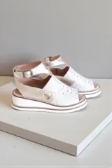 Sandalias de cuero color natural y dorado, con semi plataforma y diseño troquelado en la parte frontal. Cuentan con tira en el talón con hebilla ajustable y detalle de aplique metálico lateral.