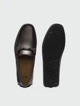 Mocasines de cuero napa color marrón oscuro, con herraje metálico con logo en el empeine y suela plana.