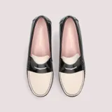Mocasín bicolor de charol negro con pala de piel blanca, detalle de antifaz clásico, plantilla interior de piel acolchada y suela fina antideslizante.