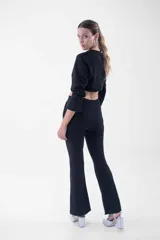 Pantalón negro de corte flare, tiro alto, con detalles de flecos de strass en los bolsillos laterales.