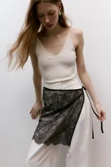 Pañuelo de cadera corto confeccionado en encaje marrón, con diseño semitransparente y tiras finas satinadas para atar en el lateral con un lazo.