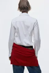 Camisa blanca de manga larga con cuello clásico y cierre frontal con botones. Confeccionada en mezcla de algodón, con canesú en la espalda y bajo redondeado.