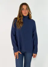 Sweater de punto color azul, con cuello alto, mangas largas y diseño holgado con costura central vertical.