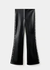 Pantalón de tiro medio efecto piel color negro, de corte flare, con adorno de tachuelas plateadas a lo largo de las costuras laterales.